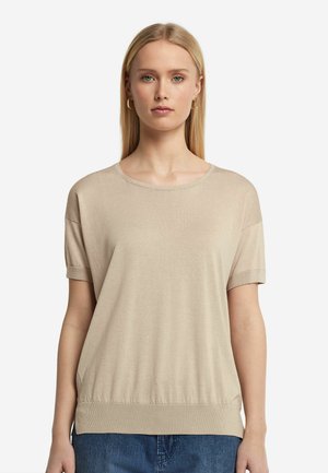 Beiges, kurzärmliges Stricktop mit rundem Halsausschnitt, lässiger Passform und gerippten Details an den Ärmeln und dem Saum, kombiniert mit blauer Denim.