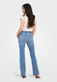 Jeans a zampa d'elefante blu con una vestibilità a vita media, design a cinque tasche e una leggera scoloritura. Il tessuto è denim con una superficie morbida.
