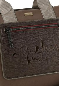 Braune Lederhandtasche mit einer Reißverschlusstasche mit roten Akzenten, eingraviertem Text "eine zeitlose Schönheit" und strukturierten Details auf der Oberfläche.