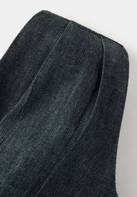 Gros plan sur un tissu denim bleu foncé avec un tissage visible et des coutures détaillées sur un vêtement.