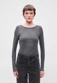 Γκρι μακρυμά�νικη ριγωτή μπλούζα με εφαρμοστή σχεδίαση. Στρογγυλή λαιμόκοψη, απαλή υφή, συνδυασμένη με ψηλόμεσα σκούρα τζιν με παρέμβαση στην τσέπη.