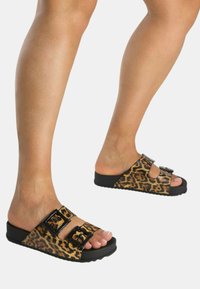 Sandali in tela con stampa leopardata, suola nera sagomata, due fibbie regolabili e design open-toe che mette in mostra unghie dei piedi curate.