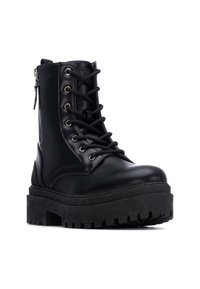 Bota de combate de cuero negro con cordones en la parte frontal, herrajes plateados, cremallera lateral y suela de goma negra gruesa con dibujo texturizado.