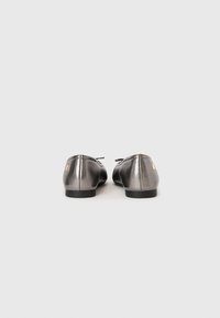 Pair of metallic gray ballet flats with black soles viewed from the back on a plain light gray background.
