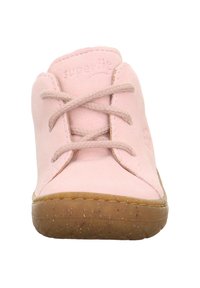Světle růžová semišová obuv s kulatou špičkou, šněrováním a gumovou podrážkou. Zahrnuje prošité detaily a jemné logo v horní části.