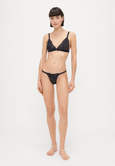 Schwarzes Spitzen-Lingerie-Set mit einem Dreieck-BH mit gewellten Kanten und einem passenden String. Beide Teile haben eine weiche Textur und zarte Details.