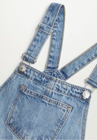 Ljusblå denimoveraller med justerbara remmar, metallspännen och en stor framficka, liggande platt på en vit bakgrund.