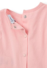 Top de algodón rosa claro con escote redondeado, cierre de botones de presión y textura suave. Incluye una etiqueta de la marca de tela en el interior.