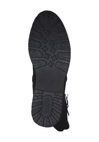 Semelle en caoutchouc noir avec un motif de bande de roulement texturé, présentant des rainures et des formes profondes pour l'adhérence. Fermeture éclair sur le côté du matériau supérieur.