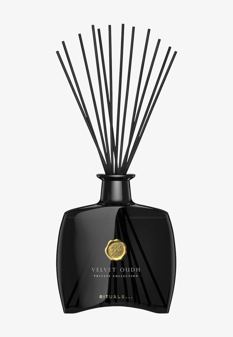 Svart glassdiffuser med buet bunn, toppet med slanke svarte pinner. Har et gullmerke og preget tekst som leser "Velvet Oudh."