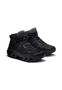 Schwarze High-Top-Wanderschuhe mit dicken, robusten Sohlen, Obermaterial aus Mesh und Synthetik sowie Schnürverschluss, entwickelt für wasserdichten Schutz.