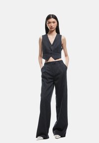 Veste cropped à rayures noires et pantalon ample, présentant un décolleté en V, des boutons et une taille plate pour un look ajusté.