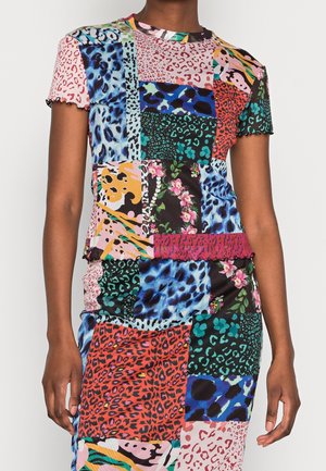 Mujer que lleva un vestido patchwork colorido con estampados mixtos de animales y patrones florales en tonos azules, rojos, rosas, amarillos y verdes.