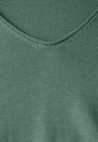 Grüner gestrickter Pullover mit V-Ausschnitt-Design. Der strukturierte Stoff weist ein feines Rippenstrickmuster mit subtilen Details entlang des Ausschnitts auf.