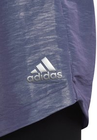 Lila idrottströja med texturerad yta. Har en silverfärgad Adidas-logotyp på nedre vänstra sidan. Sänkan har en lätt kurva. Lättviktsmaterial.