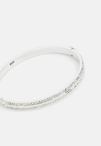 Sølvarmbånd med to parallelle rader av innebygde klare krystaller langs lengden, glatt metallisk overflate og lås.