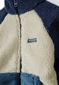 Fliisjakker, kus on tumepunane, kreemikas ja hele sinine paneel. Tekstuuriga kangas, ees lukuga ja väikese logotagiga kreemikas osas.