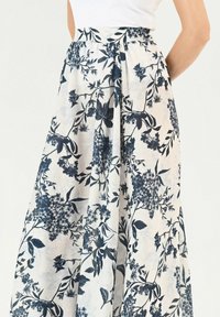 Fliederfarbene Maxi-Rock mit navyblauem Blumenmuster; verfügt über einen gerafften Bund und fließenden Stoff, der ein leichtes, luftiges Erscheinungsbild verleiht.