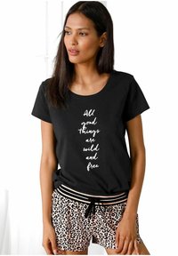 Zwarte t-shirt met korte mouwen met een witte tekstontwerp waarop staat "Alle goede dingen zijn wild en vrij," gecombineerd met roze luipaardprint shorts.