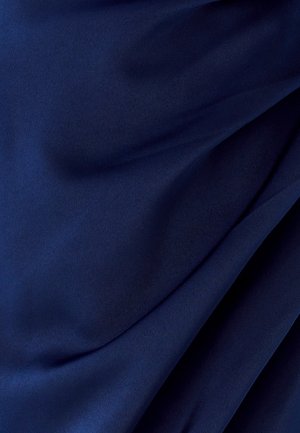 Tessuto blu scuro con morbide pieghe e superficie liscia, che mostra un drappeggio delicato e sottili riflessi di luce.