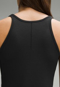 Čierny rebrovaný top na ramienka s dizajnom pretekára, so viditeľným švom a malým otvorom na zadnej strane, zobrazený na neutrálnom pozadí.