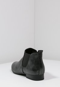 Svart chelsea-stövel gjord av texturerat faux ormskinn. Elastiska sidopaneler och en låg klack. Slät inredning.