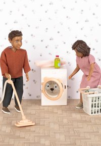 Twee actiefiguren in een was scène. Een roze wasmachine met een berengezicht, een stofzuiger, een gestreepte muur en een wasmand op een houten vloer.