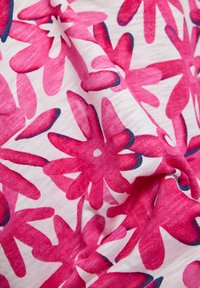 Floral fabric featuring large pink flowers on a white background, with blue accents outlining the petals, showcasing a soft, textured material.