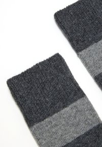 Calze di lana grigia con bordo a coste, caratterizzate da strisce orizzontali grigio scuro e grigio chiaro, texture morbida e design lavorato a maglia.