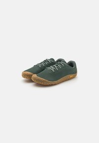 Scarpe da esterno verdi con suola in gomma, caratterizzate da dettagli testurizzati, lacci piatti e un design minimalista per un utilizzo versatile.