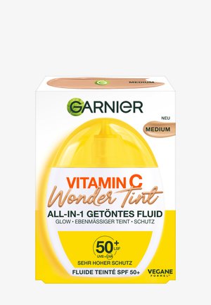 Verpackung der Garnier Vitamin C Wonder Tint, mit einem gelb-weißen Design, transparentem Deckel und braunen Akzenten, gekennzeichnet mit "Medium" und LSF 50+.