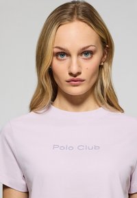 Lichtpaarse t-shirt met korte mouwen met "Polo Club" geborduurd in een lichtere tint. Glad katoen, klassiek ronde halsontwerp.