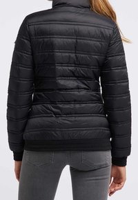 Czarna kurtka puchowa z wysokim kołnierzem i poziomym pikowaniem. Posiada dopasowaną sylwetkę oraz ściągacze przy pasie i rękawach.