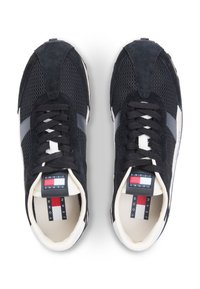 Μαύρα αθλητικά παπούτσια από δίχτυ και σουέτ με γκρι λεπτομέρειες, στρογγυλή μύτη, επίπεδα κορδόνια και ετικέτα στη γλώσσα με λογότυπο σε κόκκινο, άσπρο και μπλε.