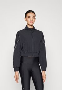 Cropped black sports jacket made of lightweight fabric, featuring a high collar, zip closure, and elastic waist, with reflective accents.