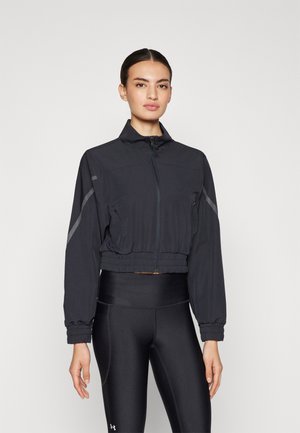 Giacca sportiva nera tagliata, realizzata in tessuto leggero, con colletto alto, chiusura zip e vita elastica, arricchita da dettagli riflettenti.