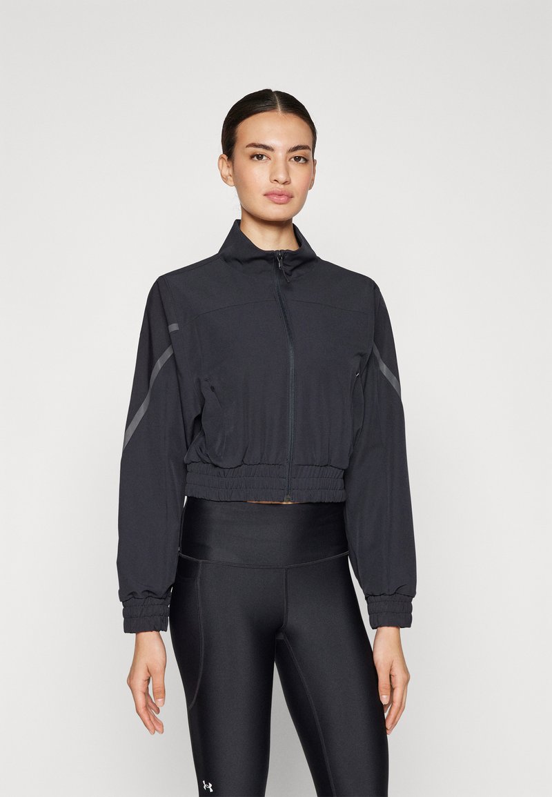 Cropped black sports jacket made of lightweight fabric, featuring a high collar, zip closure, and elastic waist, with reflective accents.
