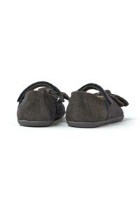 Zapatos de ante gris oscuro con textura suave, forma redondeada y correa en el tobillo, que presentan un detalle de lazo en la parte frontal.