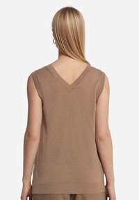 Beige ärmlös tröja med V-hals, texturerad stickad tyg, ribbad fåll och ärmhål, med en mjuk och slät finish.