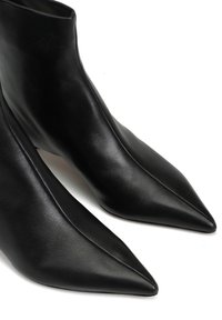 Czarne skórzane botki za kostkę z ostrymi noskami, gładką teksturą i eleganckim wzornictwem. Botki charakteryzują się czystymi liniami i minimalnymi szwami.