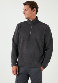 Fleece-Pullover in Dunkelgrau mit einem halben Reißverschluss-Kragen, ausgestattet mit einer weichen, strukturierten Oberfläche und geradem Schnitt für Komfort und Wärme.