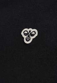 Czarna tkanina z małym białym haftowanym logo w kształcie pszczoły, umieszczonym na środku powierzchni.