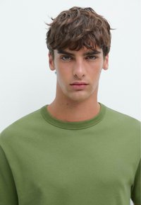 Groene katoenen sweatshirt met een ronde hals en lange mouwen, voorzien van een gladde textuur en een minimalistisch ontwerp.