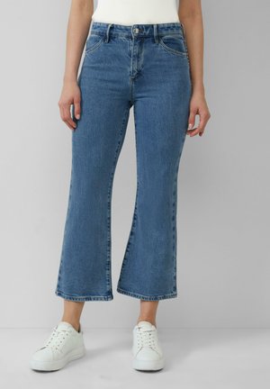 Lichtblauwe spijkerbroek met een hoge taille, brede crop-legs en voorzakken, gecombineerd met witte sneakers. Licht vervaagde textuur.