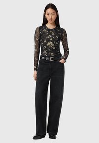 Μαύρο μακρυμάνικο τοπ από δίχτυ με λουλουδάτο σχέδιο, σε συνδυασμό με μαύρο, ψηλόμεσο, παντελόνι με φαρδιά πόδια και μαύρη ζώνη με ασημί πόρπη.