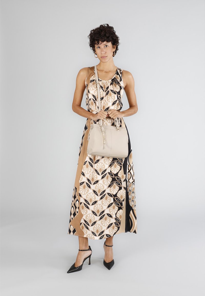 Beżowa torebka z fakturowanym wykończeniem, z podwójnymi uchwytami i zamkiem. Płynąca sukienka z kwiatowym wzorem w kolorach czarnym, kremowym i beżowym.