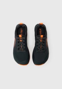Des chaussures de course noires avec des accents oranges, un dessus texturé et des lacets gris. Elles présentent un design épuré et une semelle contrastée.
