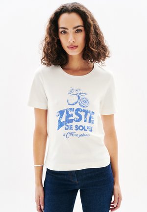 T-shirt en coton blanc avec un imprimé graphique bleu de fruits d'agrumes et le texte "ZESTE DE SOLEIL". Manches courtes avec un col rond.