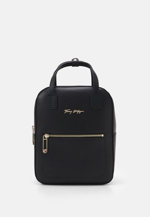 Czarna prostokątna torebka z podwójnymi górnymi uchwytami, przednią kieszenią na suwak z złotym suwakiem i złotym logo Tommy Hilfiger.