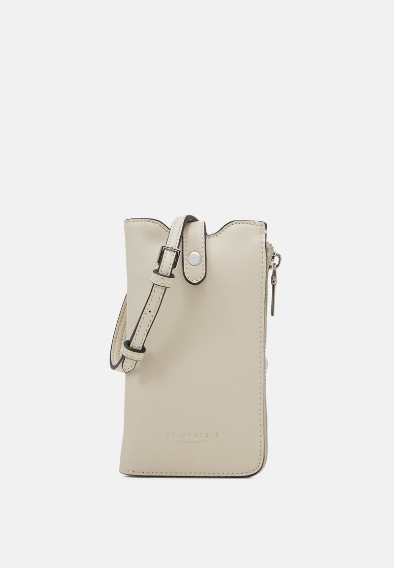 Pochette de téléphone en cuir beige clair avec une bandoulière détachable, fermée par un bouton-pression, présentant un logo discret et un détail de bord noir.